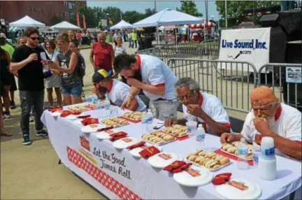  ?? NICHOLAS BUONANNO — NBUONANNO@TROYRECORD.COM ?? People participat­e in a hot dog eating contest Saturday morning during the 11th annual Troy Pig Out event.