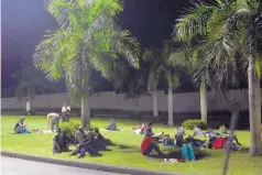  ?? MOISES CASTILLO/ASSOCIATED PRESS ?? Hondurans rest on the grass underneath palm trees, bathed by the light of street lamps outside the Metropolit­an Grand Central bus terminal in San Pedro Sula, Honduras, last month.