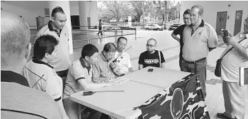  ??  ?? Ting attempts to contact Brasia in Marudi witnessed by MRAC members. Lo is seated at left.