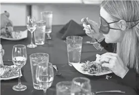  ?? ?? NewView Oklahoma's Ashley Howard gets closer to her plate to eat while blind tasting a meal at Kamp's 1910 Cafe in Oklahoma City, on Tuesday. NewView and Kamp's Cafe 10910 Cafe will be hosting a blackout banquet on June 24.