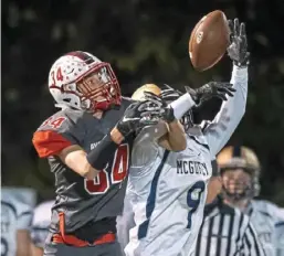  ?? Steph Chambers/Post-Gazette ?? Avonworth’s Zach Homol and McGuffey’s Tyler Smith battle for a bobbling ball, which fell incomplete. Avonworth won, 34-20.