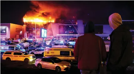  ?? ?? Emergency services vehicles are seen outside the burning Crocus City Hall concert hall following the shooting incident in Krasnogors­k. (AFP)