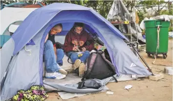  ?? STAFF PHOTOS BY DOUG STRICKLAND ?? Malcolm Amicarelli and Angie Wise live in a tent with her dog, Romeo, in a homeless encampment off East 11th Street. More than 100 people are living in the city-owned lot behind the municipal wellness center, but officials are trying to remove...