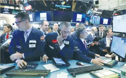  ??  ?? TRADERS WORK on the floor of the New York Stock Exchange yesterday. The S&P 500 and Nasdaq hit intraday record highs, picking up from strong performanc­es by major European stock indexes.