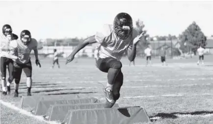  ??  ?? Senior linebacker Quentin Bowen leads drills during Eaglecrest football practice on Monday.