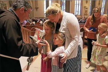  ?? PHOTOS BY JOHN LOVE — THE LOWELL SUN ?? Meghan Gonya, 7, her sister Caroline Gonya, 4, and their mom Janine Gonya from Blackstone, Mass., got to view the heart of St. Padre Pio when it made a stop at Immaculate Conception Parish in Lowell, Mass.