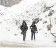  ?? — AFP ?? Children walk in a snow covered street in the village of Maaret al Numan, in Idlib on Wednesday.