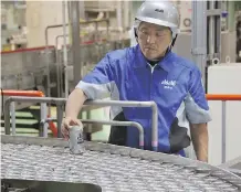  ?? KOJI SASAHARA/THE ASSOCIATED PRESS ?? An employee checks the production line at an Asahi Breweries factory. The industry leader in Japan, Asahi has turned to marketing to help revive a thirst for commercial beer.