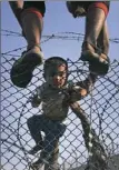  ?? Lefteris Pitarakis/AP ?? Syrian refugees lift a child over the border into Turkey from Syria. Tens of thousands of Syrians are fleeing intense fighting in northern Syria.