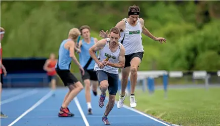  ?? WARWICK SMITH/STUFF ?? Zac Topping takes the baton from Brayden Grant to complete the last 400 metres in the 4x400m relay, and a win for the Palmerston North Athletics team.