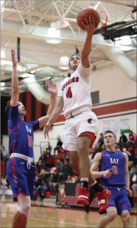  ?? RANDY MEYERS — FOR THE MORNING JOURNAL ?? Elyria’s Caleb Rodgers drives past Bay’s Jake Martin and scores during the first quarter on Dec. 17.