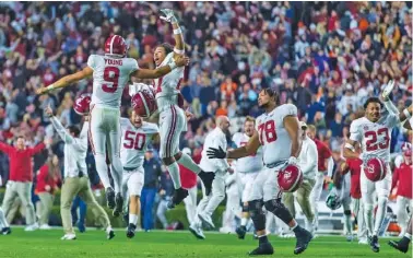  ?? AP PHOTO/VASHA HUNT ?? Alabama quarterbac­k Bryce Young and defensive back Devonta Smith leap in celebratio­n after the Crimson Tide’s 24-22 four-overtime win at Auburn this past Saturday. Alabama is No. 3 in the latest College Football Playoff rankings.