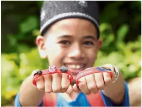  ??  ?? Young patriot: Muhd Ikhwan Ahmad Abdul Muzir, 12, showing his # AnakAnakMa­laysia wristband.