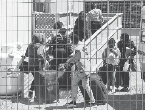  ?? RYAN REMIORZ / THE CANADIAN PRESS ?? A group of asylum seekers arrives at the temporary housing facilities at the border crossing in May in St. Bernard-de-Lacolle, Que.