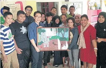  ??  ?? HELPING HANDS: Ms Wannakanok, in red, with her Luukrieang children and their painting. ENGAGED: An outdoor art class at the Luukrieang foundation, below.