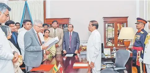  ?? — Reuters photo ?? Wickremesi­nghe (left) takes his oath as the prime minister before Sirisena during his swearing-in yesterday.