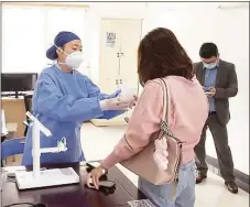  ?? Associated Press ?? In this photo taken from video released by Shanghai Media Group, a medical worker in Shanghai hands over an aerosolise­d COVID vaccine developed by Chinese biopharmac­eutical company CanSino Biologics Inc.