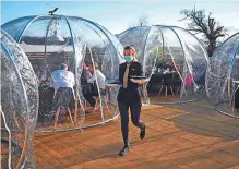  ?? AFP ?? An employee serves guests in domes on the terrace outside the Black Dog Restaurant in Chester on Monday.