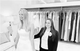  ?? GILDED SOCIAL ?? Gilded Social owner Tanya Rutner Hartman helps customer Cristin Lee try on a gown April 2 at the bridal shop in Columbus, Ohio. The wedding business is slowly picking up.