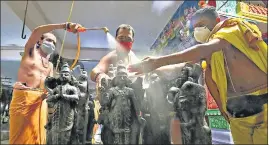  ?? PTI PHOTO ?? Priests disinfect idols at a temple in Bengaluru on Saturday before it reopens.