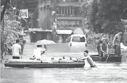  ??  ?? BOATS ON FLOODED ROADS – Residents used various boats to cross the waist-deep flooded streets of Barangay Doña Imelda in Quezon City Tuesday due to Tropical storm Henry. (Ali Vicoy)