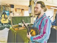  ??  ?? Rappahanno­ck musician Forrest Marquisee strums the mandolin his father made for him from scraps in 2003, the first instrument built by the woodworker.