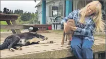  ?? AP PHOTO ?? In this April 5 photo, longtime resident Paula Ellis plays with her dogs outside her home in Tiller, Ore. Ellis spent her childhood in Tiller hunting and riding horses and now worries about what will happen to the tiny, dying timber town.