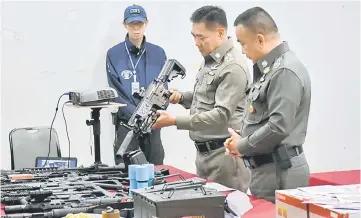  ??  ?? Chaijinda (centre) holds a confiscate­d weapon during a news conference at the Royal Thai Police headquarte­rs in Bangkok. — Reuters photo