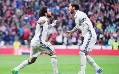  ?? — AFP ?? MADRID: Real Madrid’s Brazilian defender Marcelo (L) celebrates a goal with Real Madrid’s defender Sergio Ramos during the Spanish league football match Real Madrid CF vs Valencia CF at the Santiago Bernabeu stadium.