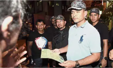  ??  ?? In search of
illegals: Home Ministry’s Deputy Minister Datuk Mohd Azis Jamman (blue shirt) and Mustafar (third from right) questionin­g a foreigner during a raid in Taman Subang Mas in Subang Jaya. — Bernama