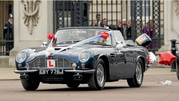  ?? GETTY IMAGES ?? Prince William and Catherine, Duchess of Cambridge, leave Buckingham Palace after their Wedding reception in Prince Charles’ vintage Aston Martin DB6 Volante in 2011. The car runs on wine.