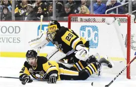  ?? — AFP ?? PITTSBURGH: Justin Schultz #4 of the Pittsburgh Penguins reaches for the puck while laying on the ice against the New York Rangers at PPG PAINTS Arena on Monday in Pittsburgh, Pennsylvan­ia.