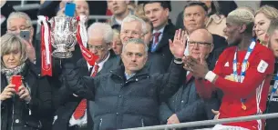  ??  ?? United manager Jose Mourinho holds the trophy as Paul Pogba, right, looks on.