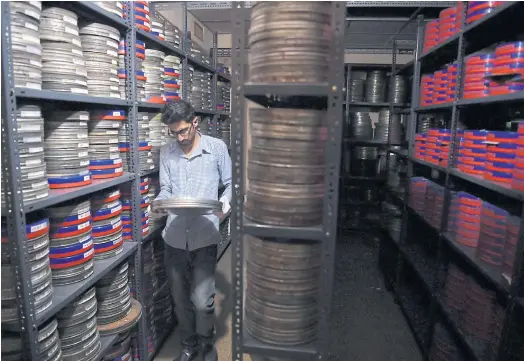  ??  ?? REELING FROM HISTORY: An employee at the Afghan Film company. The rediscover­ed footage of once forbidden films covers tens of thousands of hours.