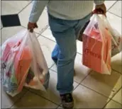  ?? THE ASSOCIATED PRESS ?? A shopper at the Brea Mall in Brea, Calif., carries bags full of packages. Amid the holiday decoration­s and cheerful ads, splurging is not an option for many Americans struggling to get by.