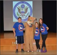  ?? PHOTO BY LAURA CATALANO - FOR MEDIANEWS GROUP ?? 6th graders Gus Smith, Riley Serfass and Emory Harmanos pose with the Wildcat before a slide bearing the National Blue Ribbon seal. The three students spoke during the ceremony.