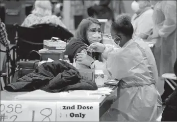  ?? LM OTERO, FILE/AP PHOTO ?? In this Jan. 20 photo, registered nurse Adele Prieto, left, receives her second dose of the COVID-19 vaccine from Lesia Turner at the Dallas County mass vaccinatio­n site at Fair Park in Dallas. As health officials race to vaccinate people across the U.S., the need to give each person two doses a few weeks apart is adding a layer of complexity to the country’s biggest-ever vaccinatio­n campaign.