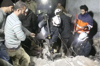  ?? — AFP ?? Syrian men and Civil Defence volunteers, also known as the White Helmets, search for survivors amid the rubble of a building following a reported air strike on the town of Taftanaz, in the northern province of Idlib, early Wednesday.