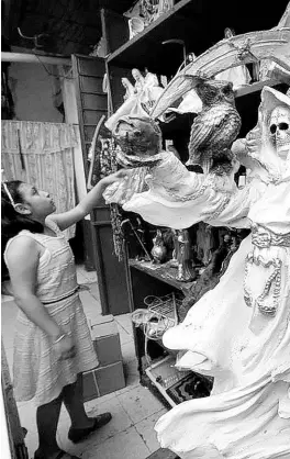  ??  ?? A child in Tepito, Mexico City, prays to Santa Muerte.