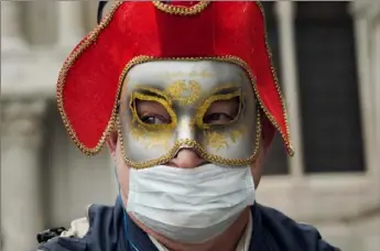  ?? Renata Brito/Associated Press ?? A Russian tourist dons both a carnival mask and a protective face mask Tuesday as he visits St. Mark’s Square in Venice, Italy.