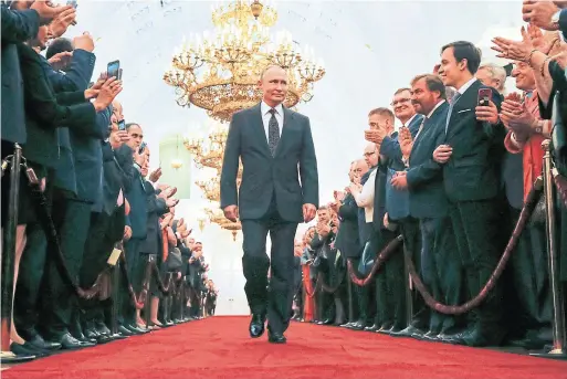 ?? ALEXANDER ZEMLIANICH­ENKO/AFP/GETTY IMAGES ?? Before his speech, Vladimir Putin donned a suit jacket and walked, for considerab­le time and with signature swagger, down the red-lined Kremlin halls to a limousine.