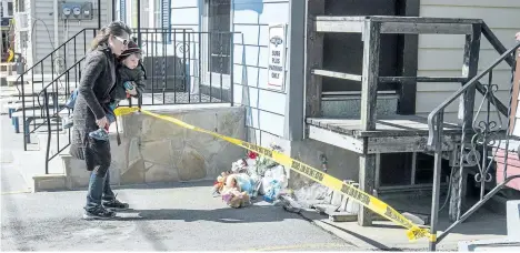  ?? BOB TYMCZYSZYN/POSTMEDIA NETWORK ?? Kelly Vidal and her son, Ronnie, add to the stuffed animals and flowers in front of the St. Catharines Queenston Street residence of Nathan Dumas. Police have issued a Canada-wide warrant for the boy’s stepfather Justin Kuijer who is suspected in the...