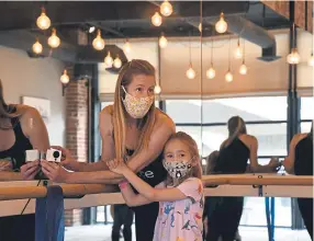  ?? Photos by Kathryn Scott, Special to The Denver Post ?? Barre Forte studio owner Sage Fennig is joined by her daughter, Elise, as she sets up a camera for instructor Jenn Gilliam so her barre class can be live-streamed.