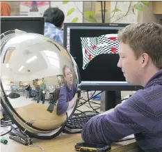  ??  ?? Cody Ede uses a concave mirror for an aid in projecting a computer control panel on the walls of room in his Aspecta project.