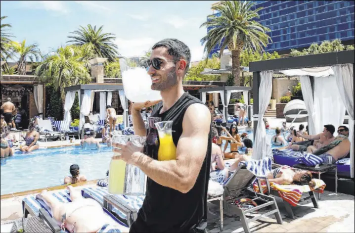  ?? Bizuayehu Tesfaye Las Vegas Review-Journal @bizutesfay­e ?? Model cocktail server Talih Kadi carries drinks as he prepares to serve poolside guests Saturday at the M Resort in Henderson.