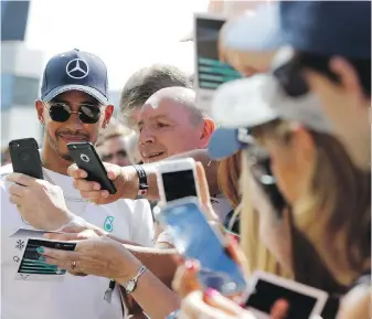  ??  ?? Mercedes driver Lewis Hamilton of Britain signs autographs and poses for photograph­s in the pit lane at the Silverston­e racetrack in Silverston­e, England, on Thursday.