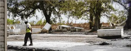  ?? PHOTOS BY GERALD HERBERT/ASSOCIATED PRESS ?? A worker walks through a heavily damaged cemetery in Ironton, La., on Sept. 27. A Louisiana task force is working to gather vaults and caskets disrupted from their burial sites by Hurricane Ida and rebury them, but the task is still ongoing.