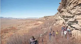  ?? FIRST PEOPLES BUFFALO JUMP STATE PARK ?? Hikers at First Peoples Buffalo Jump State Park closely inspect the cliff face where for hundreds of years Native peoples drove harvested and processed buffalo.