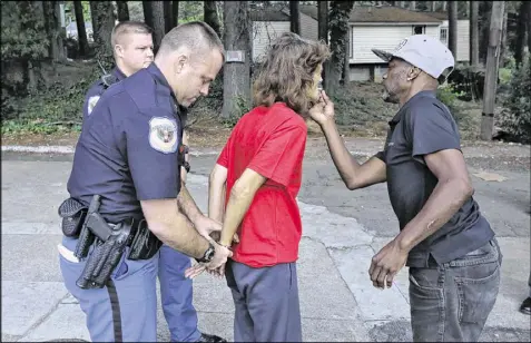  ??  ?? A suspect gets help with the final drag on a cigarette as she is being arrested on a parole violation. Cobb County Police Officer Jarod Peer (left, putting on handcuffs) has been using a body camera for almost a month.