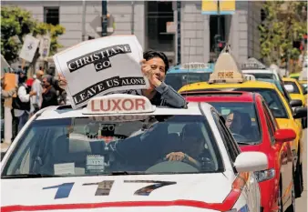  ??  ?? Taxi driver Danny Nguyen joins a line of cab drivers and owners protesting by circling City Hall before the meeting of the San Francisco Municipal Transporta­tion Agency.